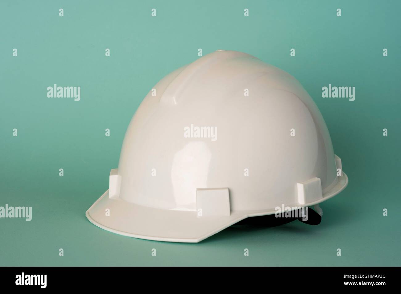 casco protettivo bianco su sfondo turchese, sicurezza, protezione del lavoro. Foto Stock