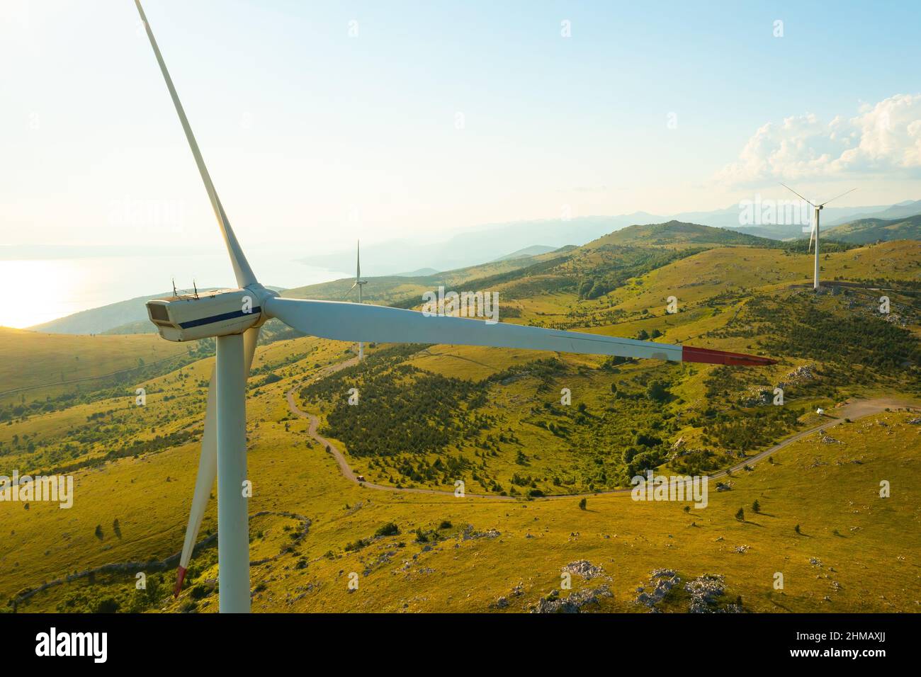 Mulini a vento con grandi pale generano energia elettrica pulita che funziona in stazione in altopiano selvaggio vicino al mare Adriatico per la protezione ambientale vista aerea Foto Stock