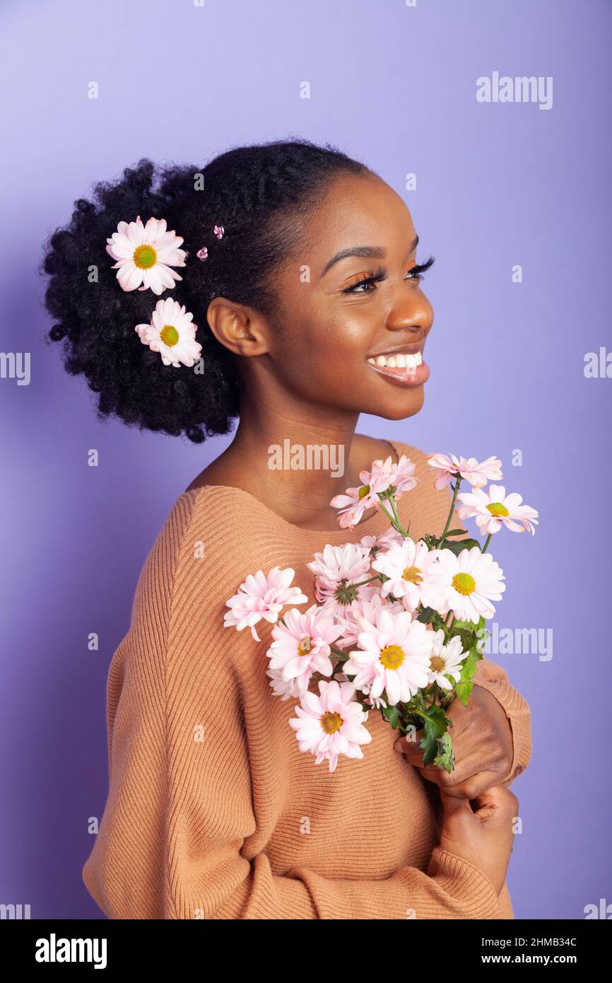 Una donna britannica nera con fiori nei suoi capelli legati alla schiena. Foto Stock