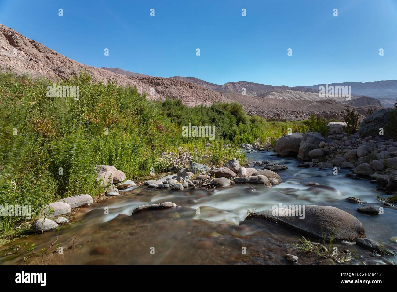 Effetto seta sul fiume con vegetazione e montagne sullo sfondo Foto Stock