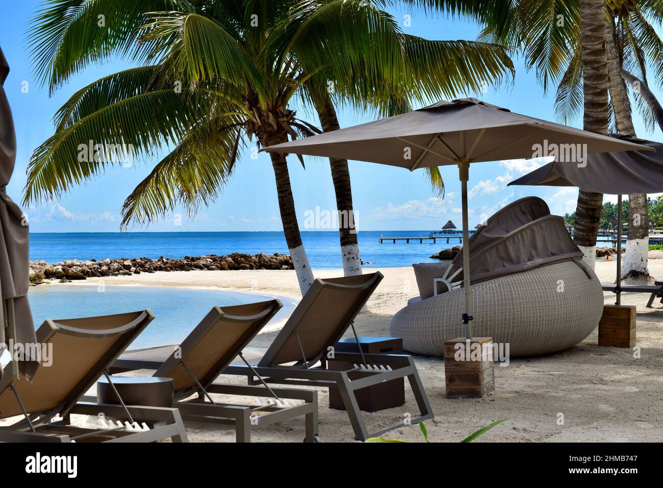 Sedie a sdraio e un divano letto rotondo con baldacchino sulla spiaggia di San Pedro, Belize in una giornata luminosa e soleggiata. Foto Stock