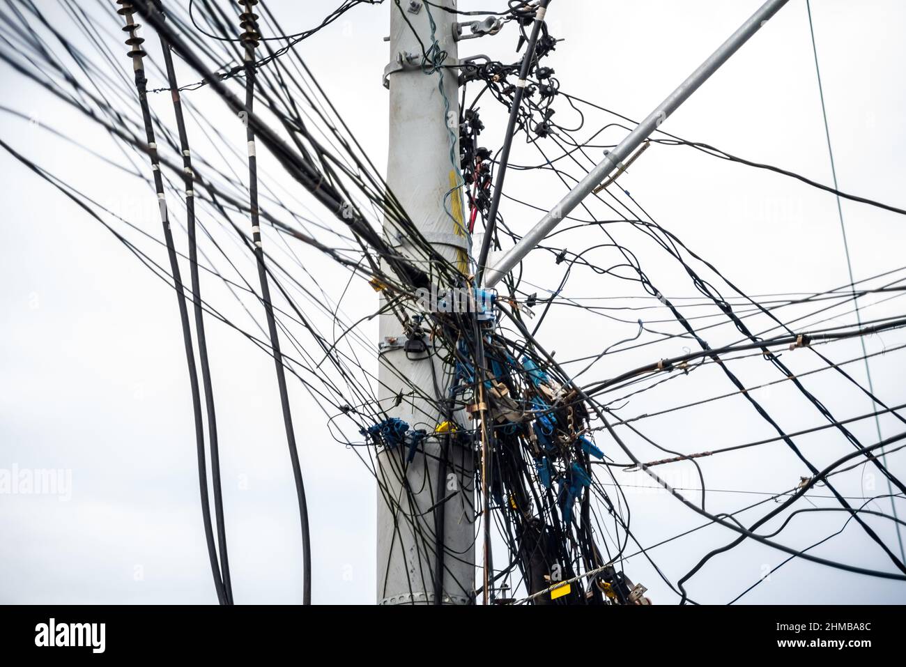 Groviglio di fili e cavi su un palo contro il cielo limpido. Salvador, Bahia, Brasile. Foto Stock