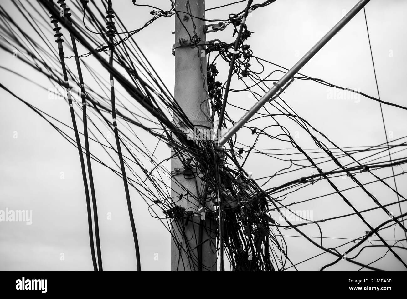 Groviglio di fili e cavi su un palo contro il cielo limpido. Salvador, Bahia, Brasile. Foto Stock