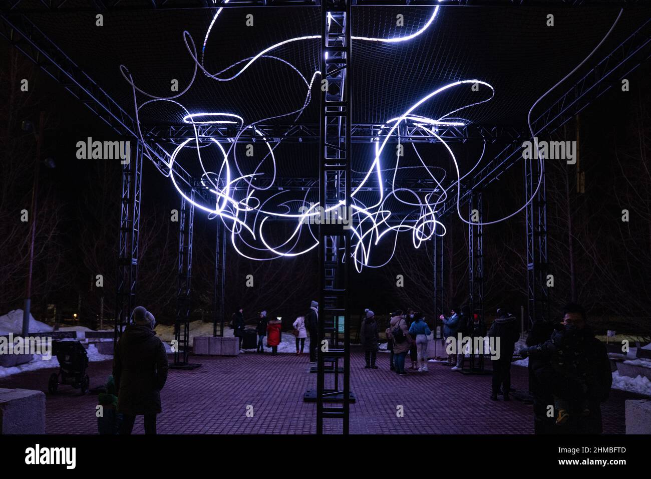 Toronto, Canada. 07th Feb 2022. Persone viste in un'installazione artistica all'aperto, ‘Pressure’ di Hans E. Madsen e Frederik D. Houds, un pezzo costituito da una serie di 300 metri di luci a LED RGB pulsanti che assomigliano a un doodle, avvolto intorno a una grande costruzione. La mostra invernale Nordic Lights Outdoor è una mostra di arte leggera nordica e canadese presso il Toronto Harbourfront Centre, co-prodotto con Fjord Studio. (Foto di Katherine Cheng/SOPA Images/Sipa USA) Credit: Sipa USA/Alamy Live News Foto Stock