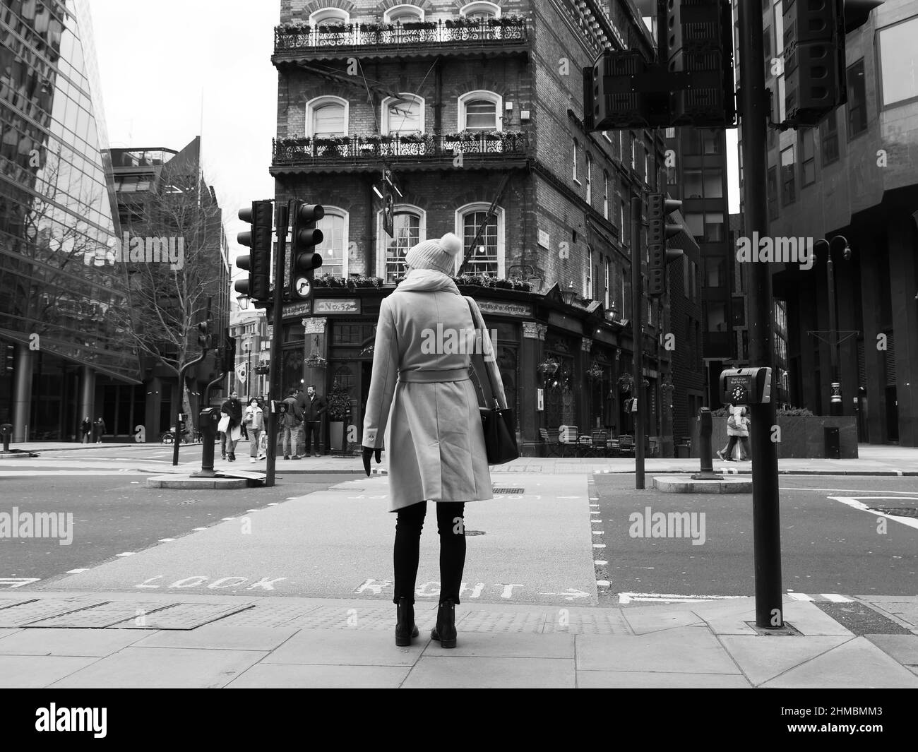 Londra, Greater London, Inghilterra, febbraio 05 2022: Donna in abbigliamento invernale, tra cui cappotto e guanti, si trova a un passaggio pedonale su Victoria Foto Stock