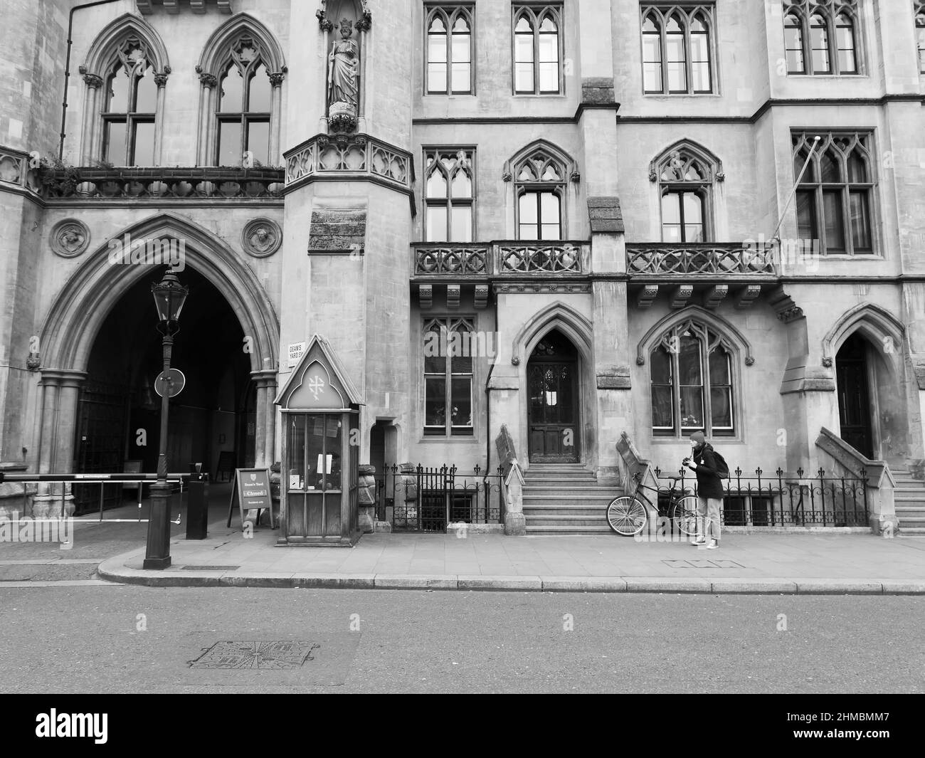 Fotografo femminile con bicicletta accanto alla proprietà e arco che conduce a Deans Yard, Westminster, Londra. Foto Stock