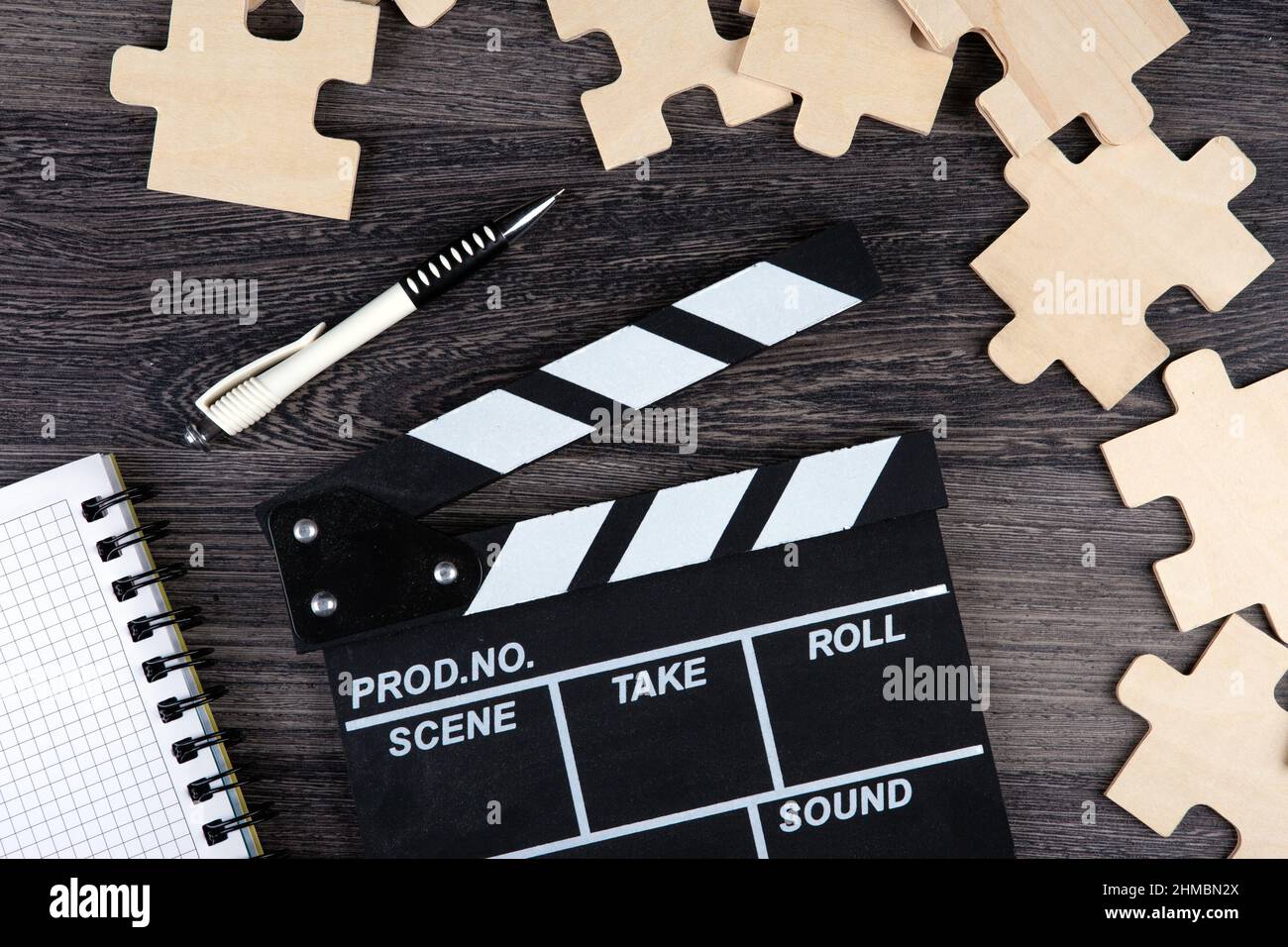 clapper cinematografico con blocco note, penna e pezzi di puzzle su una vista da tavolo Foto Stock