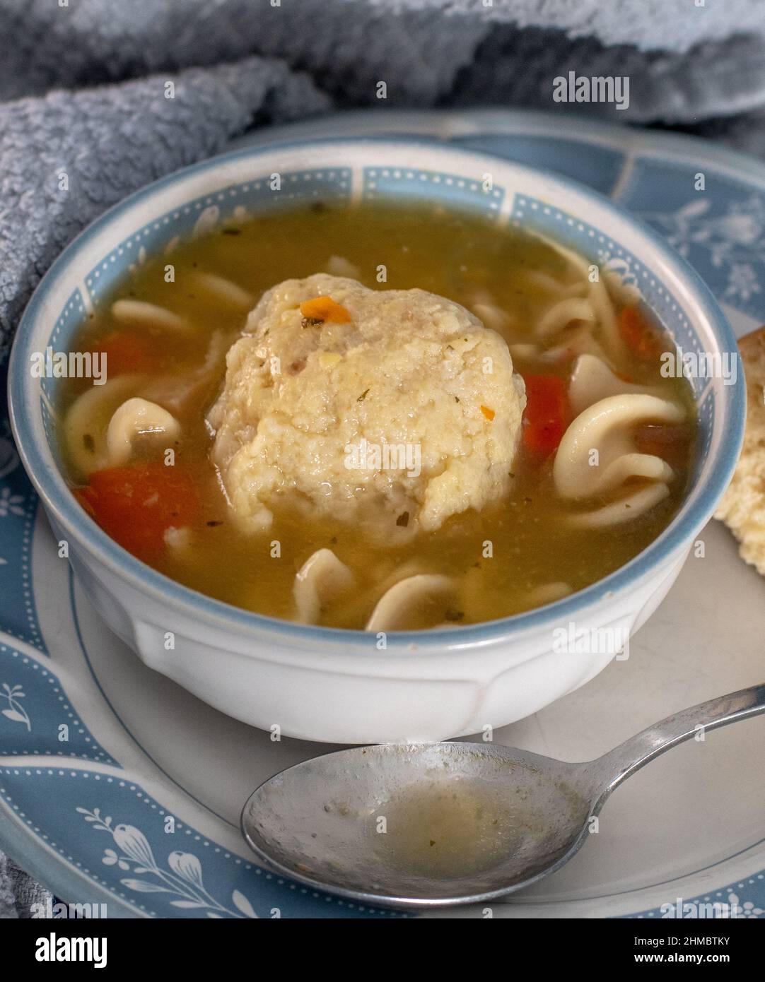 Una perfetta palla di mattone si trova in una ciotola calda e saporita di zuppa di pollo con spaghetti e carote, sedano e pollo Foto Stock