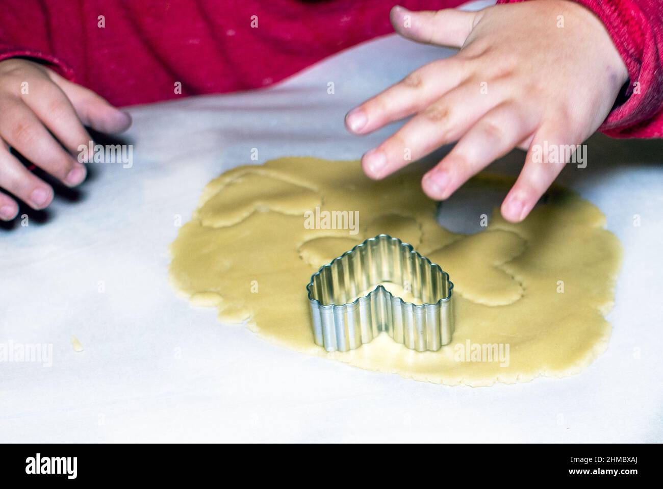 la piccola mano informa i cuori nell'impasto dei biscotti Foto Stock