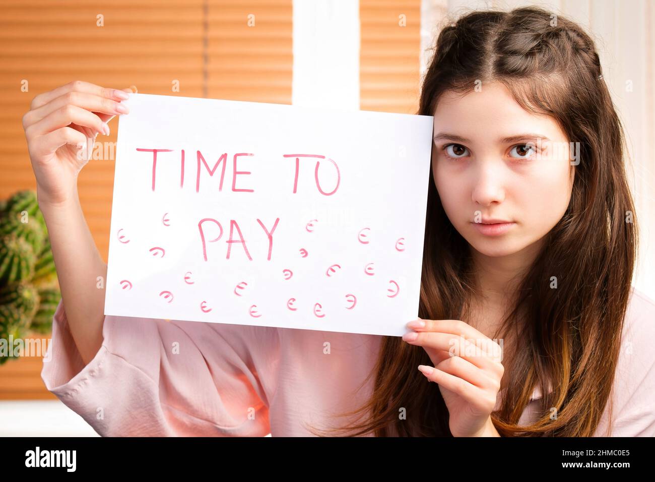 Giovane donna preoccupata che tiene in mano un documento con un'iscrizione di tempo per pagare, crisi in una cattiva situazione finanziaria. Foto Stock