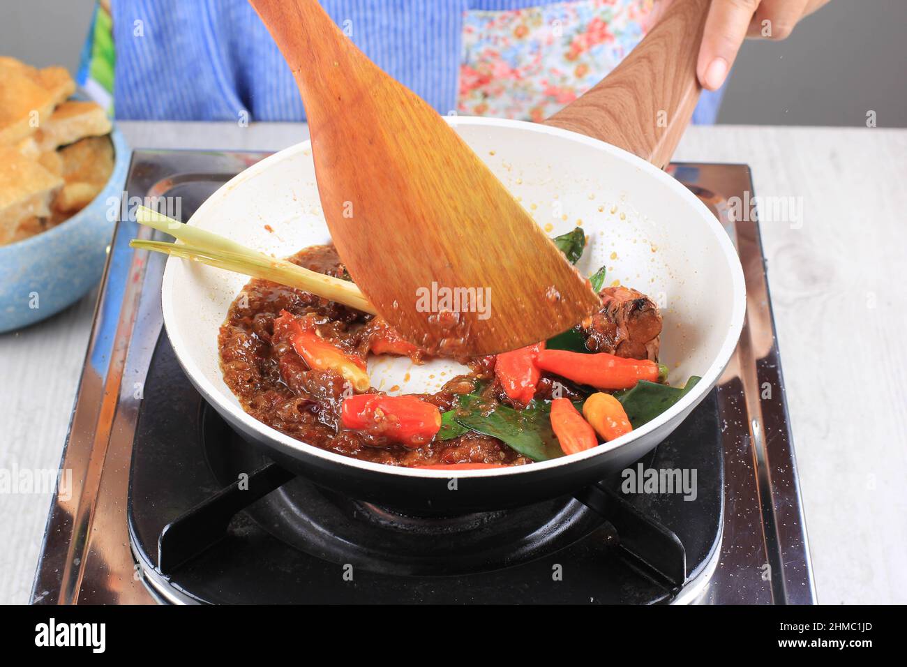 Processo di cottura Saute Sambal Sambel o salsa piccante con citronella su una padella in cucina, Sauteiing Spices femminile mano Foto Stock