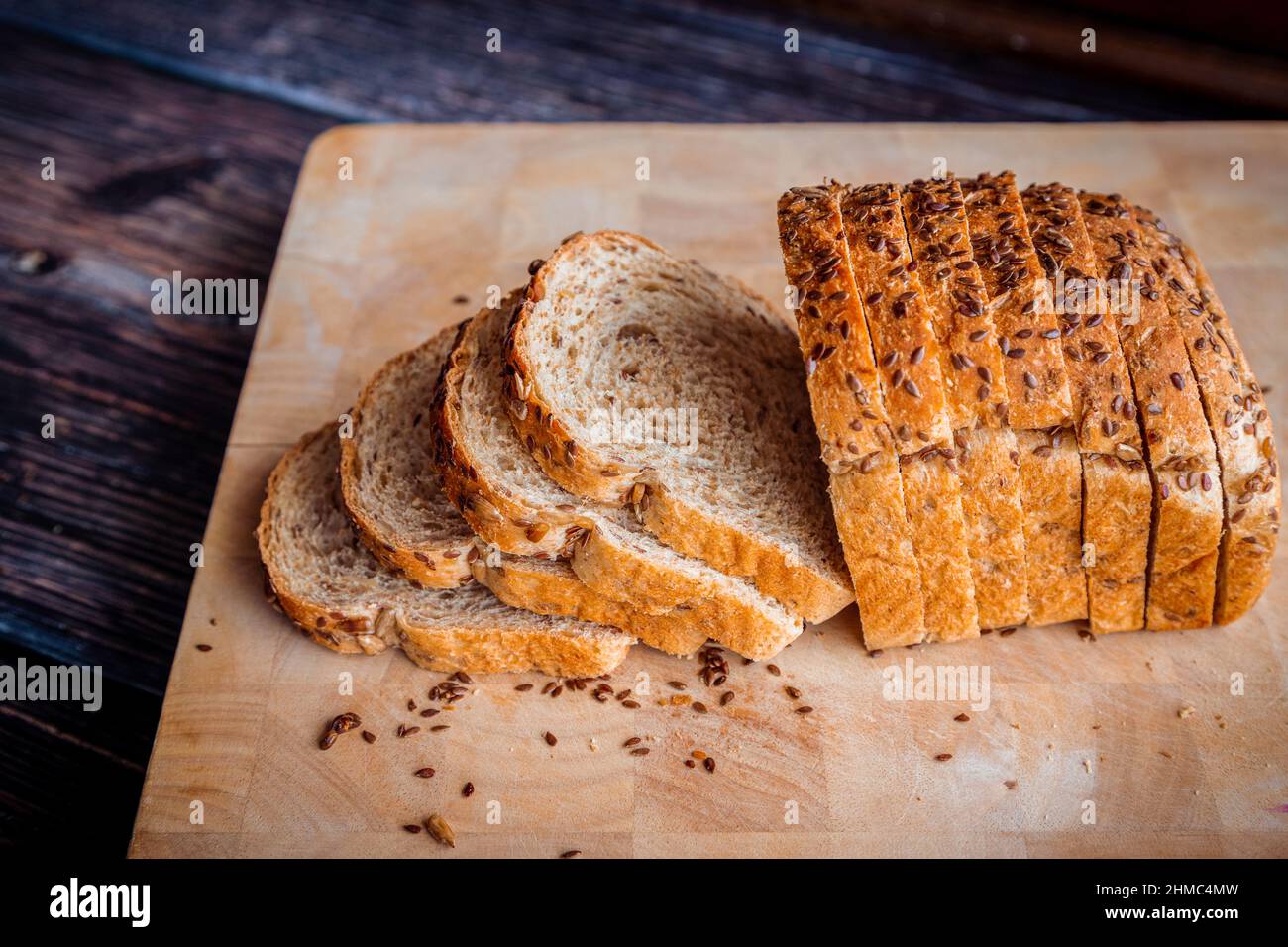 Pane di semi di lino di grano integrale appena sfornato, affettato su un rustico tavolo di legno con spazio copia. Foto Stock