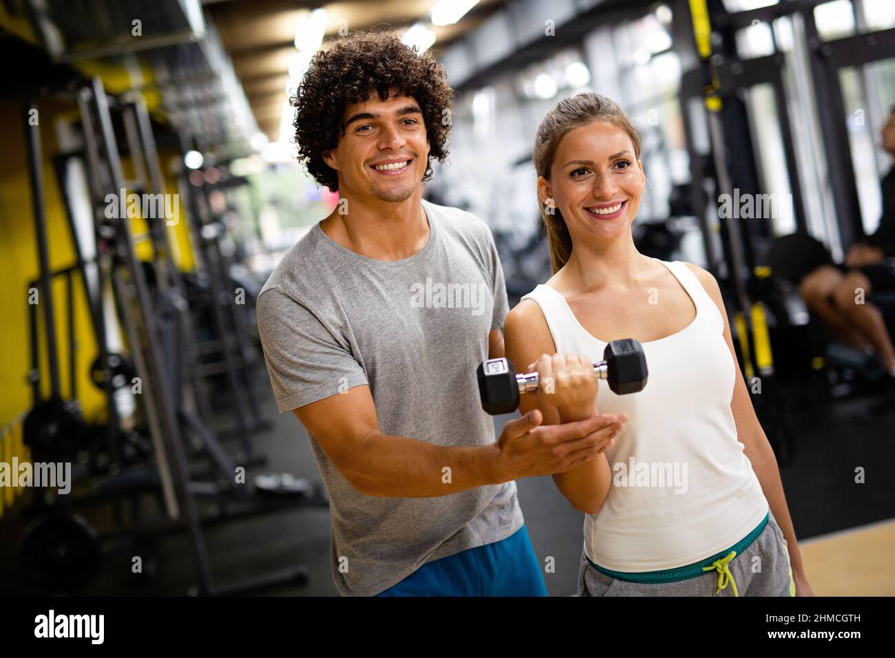 Fit donna felice con il suo personal fitness trainer in palestra esercitandosi con i manubri Foto Stock