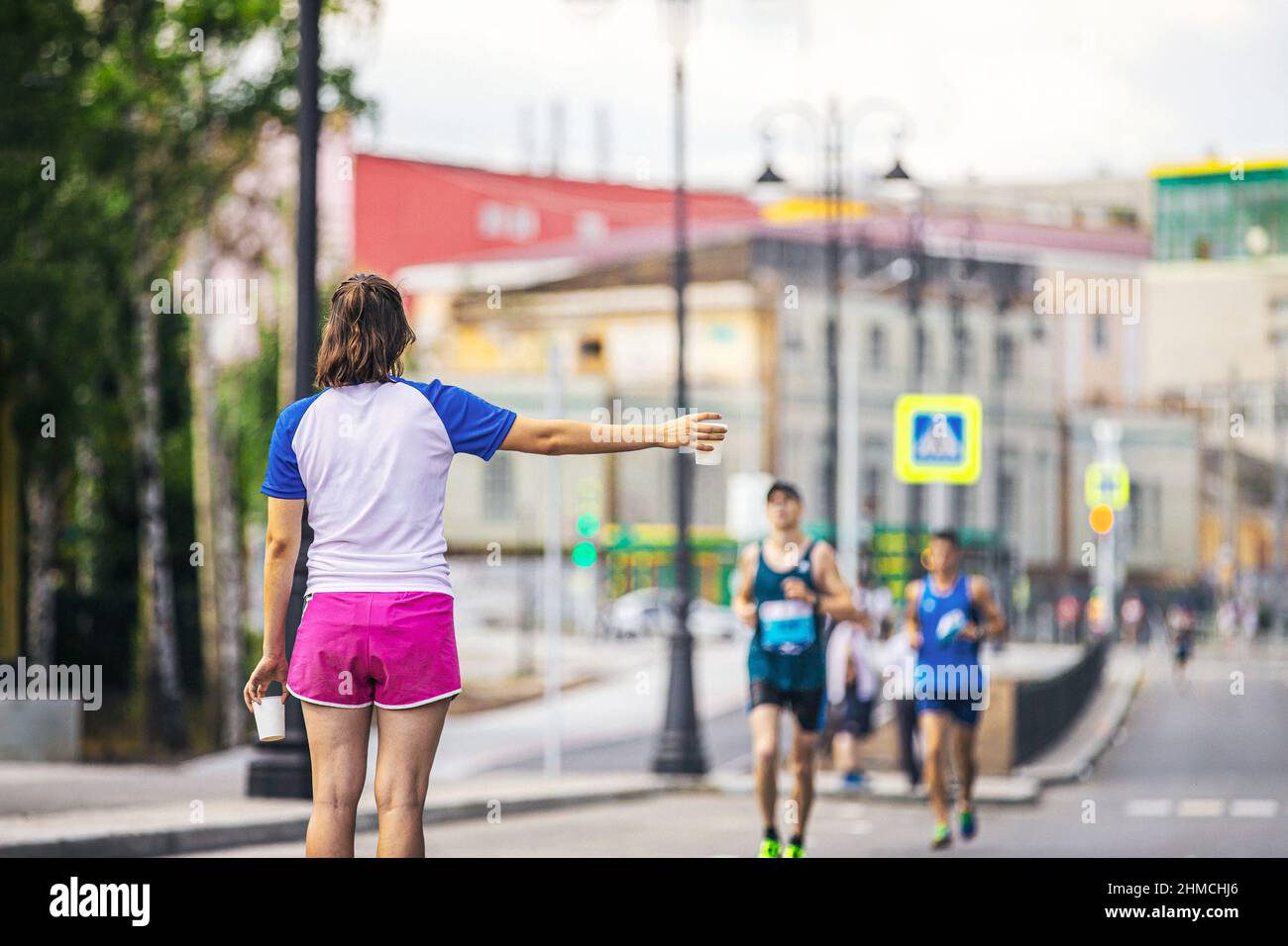 volontario ragazza al punto d'acqua con tazza di plastica di acqua durante la maratona Foto Stock