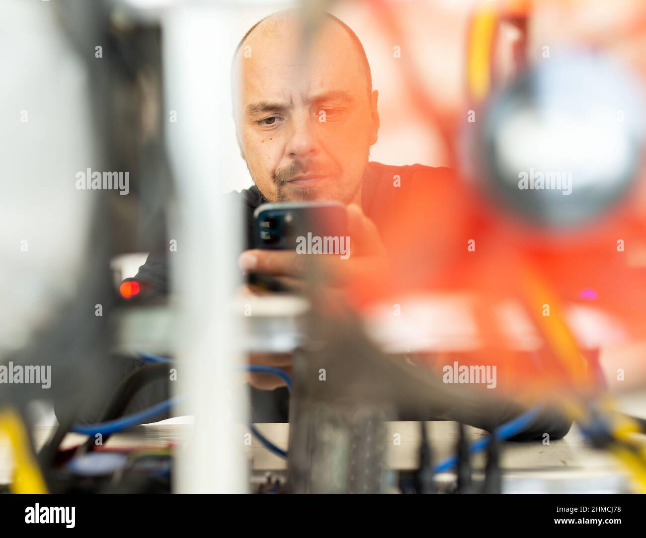 Programmatore giovane che regola il carro di estrazione a criptovaluta per impostazioni operative ottimali. Foto di alta qualità Foto Stock