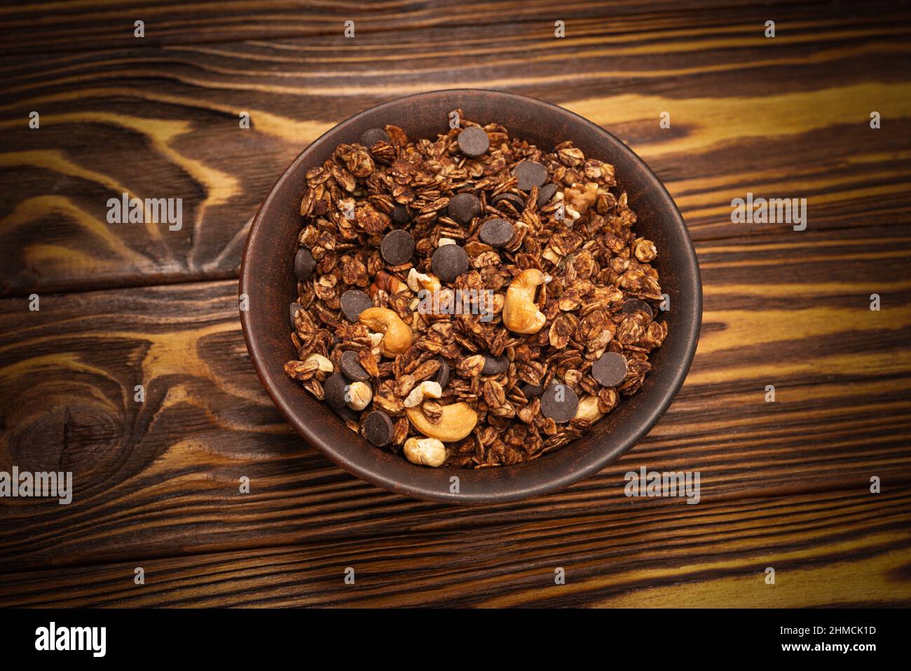 Cereali al cioccolato con noci in una ciotola su sfondo di legno. Foto Stock