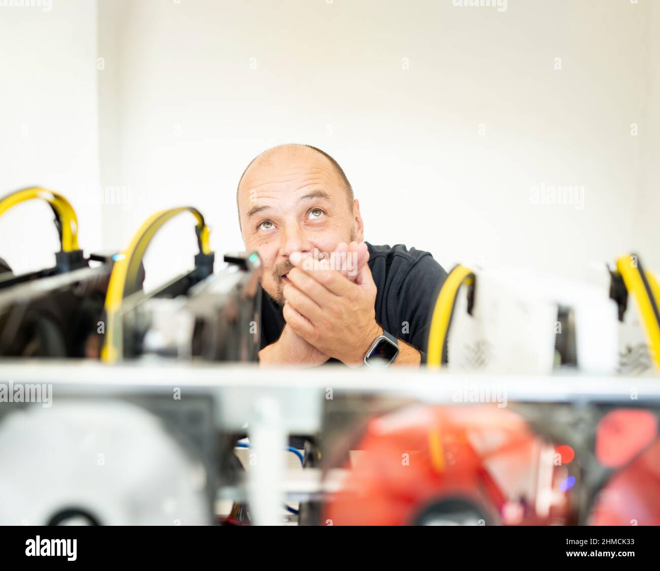Programmatore giovane che regola il carro di estrazione a criptovaluta per impostazioni operative ottimali. Foto di alta qualità Foto Stock