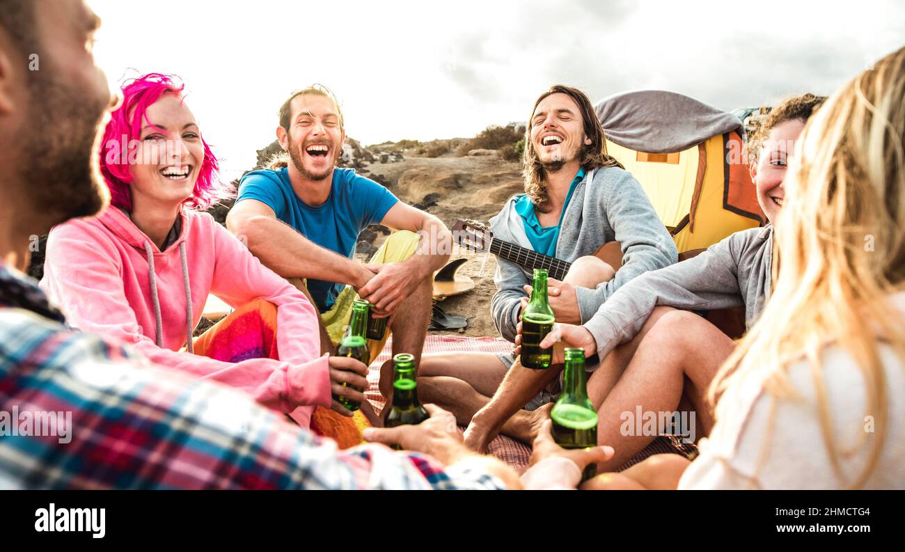 Hippie persone che si divertono insieme al Beach camping party - concetto di viaggio stile di vita con felici hippster viaggiatori che suonano la chitarra e bevono in bottiglia Foto Stock