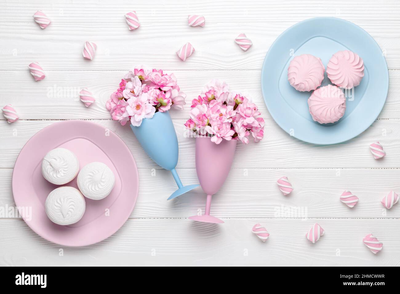 Due wineglass con fiori di primavera come bevanda. Dessert al mattino per colazione, vista dall'alto. Fiore di ciliegio su un tavolo di legno bianco. Design piatto. Foto Stock