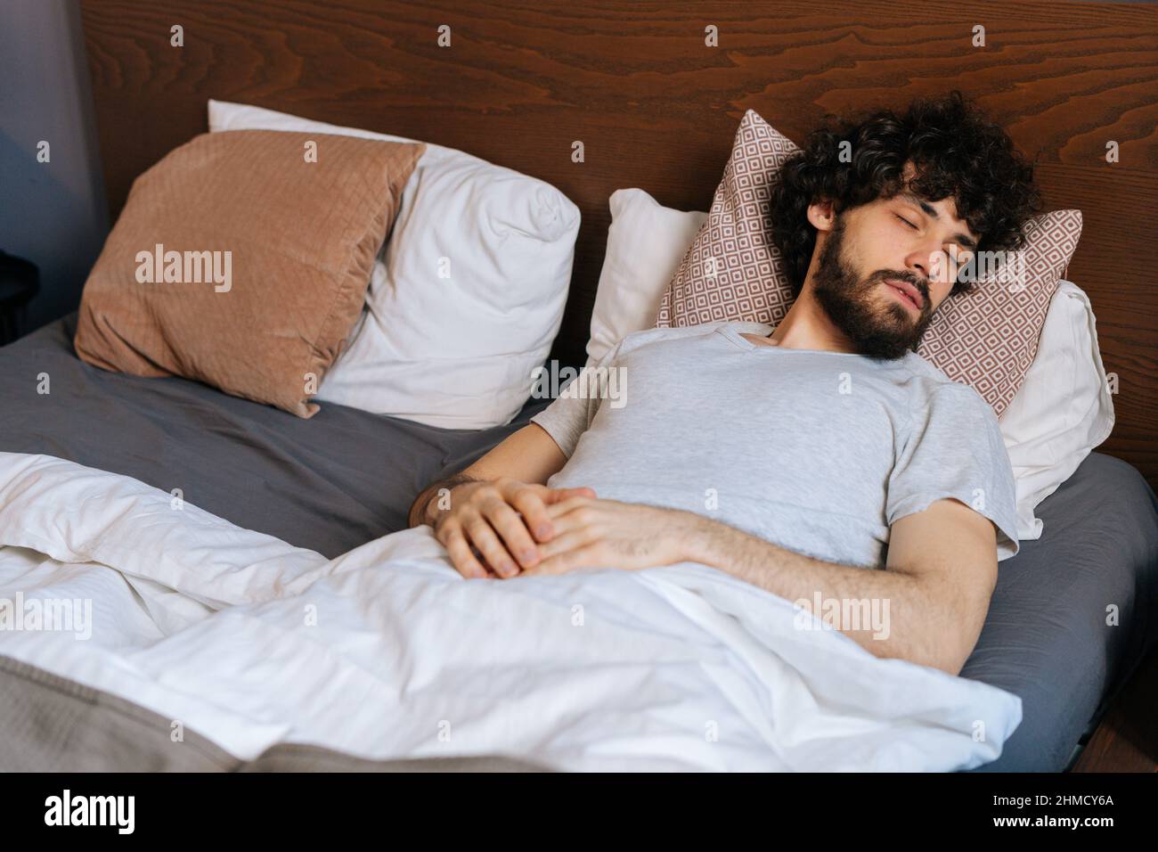 Vista ad alto angolo del bel giovane uomo che dorme tranquillamente  adagiato sul retro in un ampio e comodo letto matrimoniale sotto coperta  bianca Foto stock - Alamy