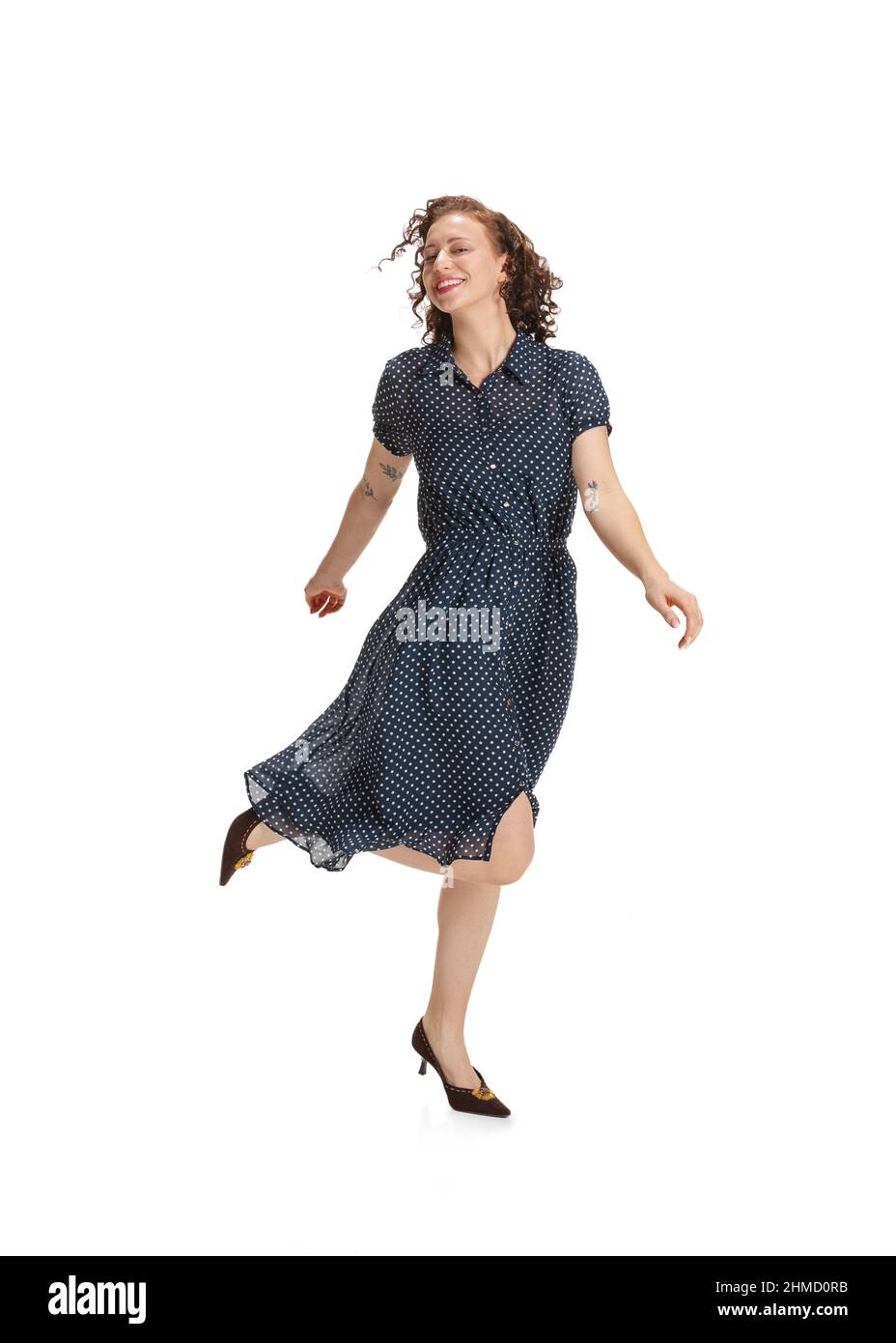 Ritratto di giovane bella eccitato ragazza in stile retrò abito, moda di 70s, 80s anni ballando isolato su sfondo bianco studio con copyspace Foto Stock