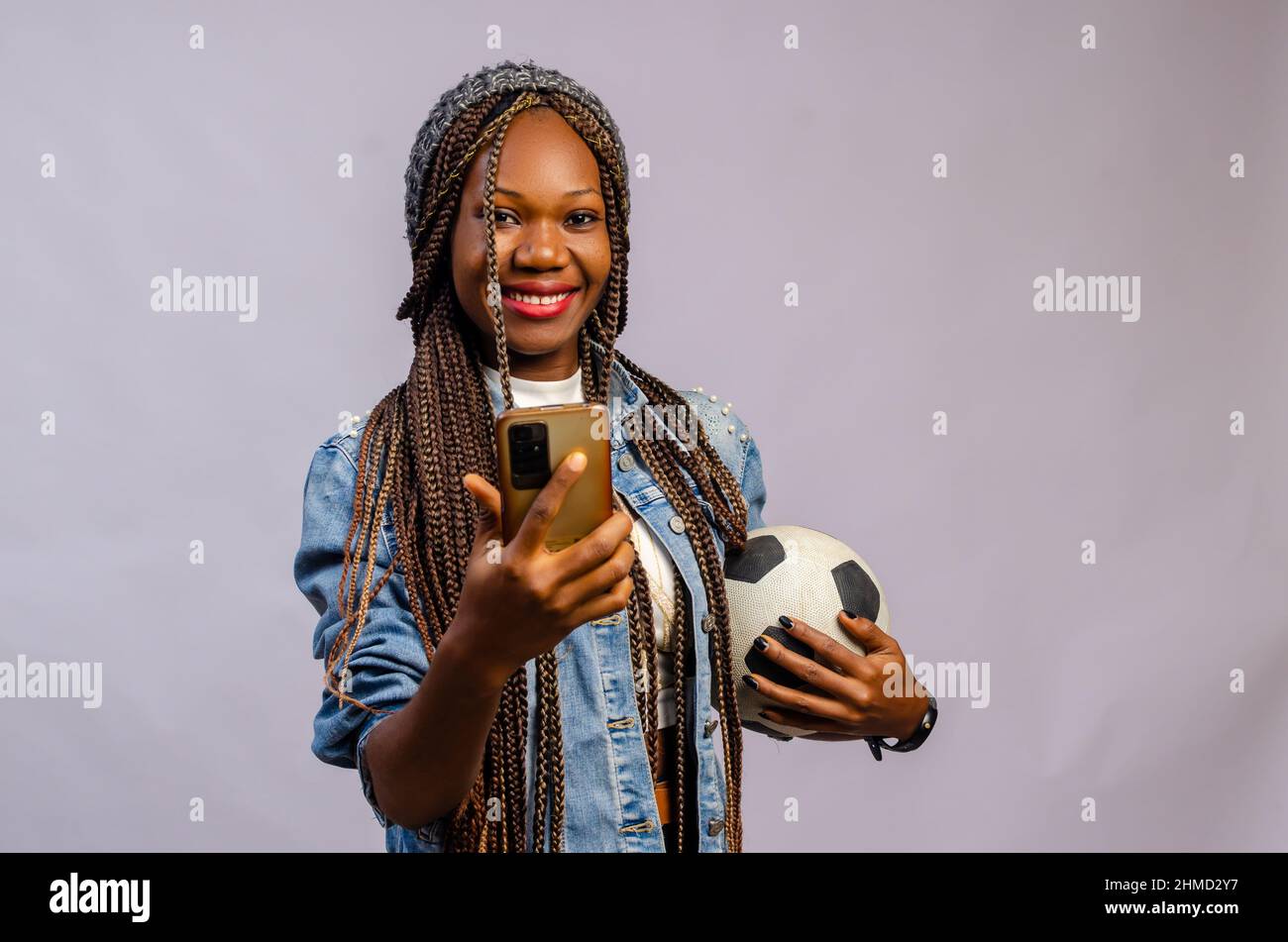 giovane donna africana fare scommesse sportive online utilizzando l'applicazione mobile. Foto Stock