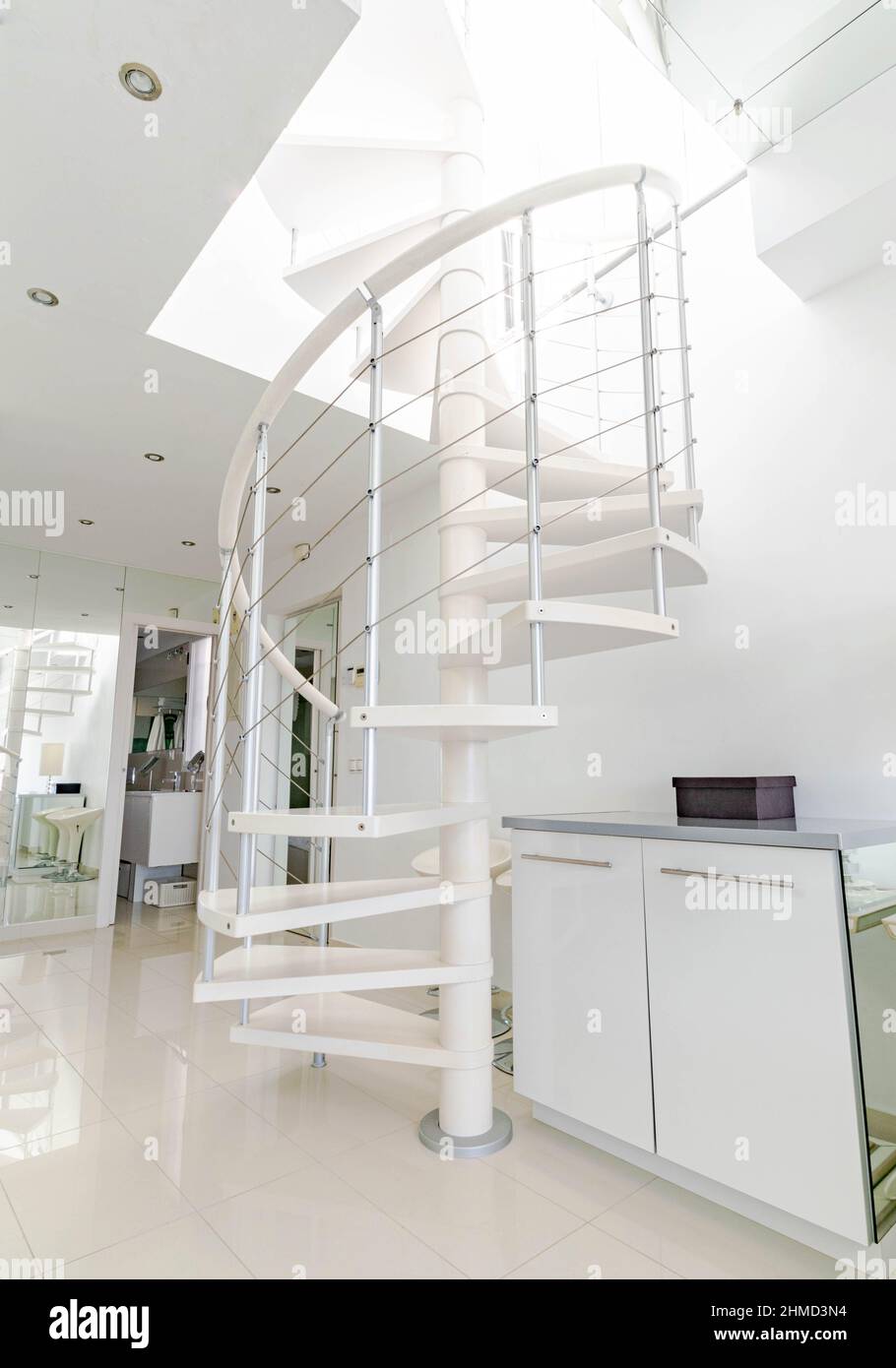 una scala a chiocciola bianca che conduce ad una terrazza al piano superiore all'interno di una casa a tema bianco Foto Stock