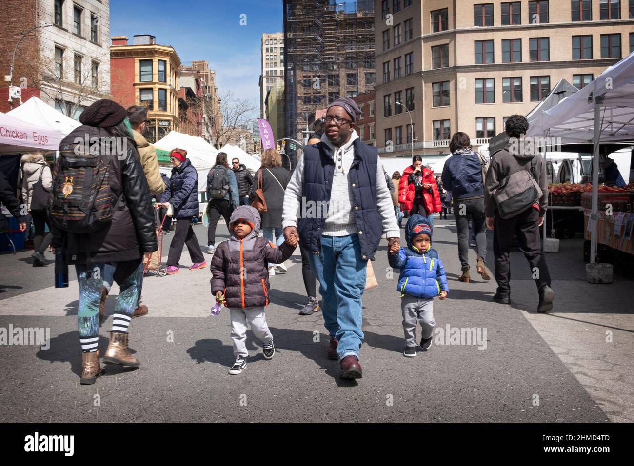 In un freddo primo giorno di Primavera un nonno cammina con i suoi 2 nipoti attraverso l'Union Square Green Market a Manhattan, New York City. Foto Stock