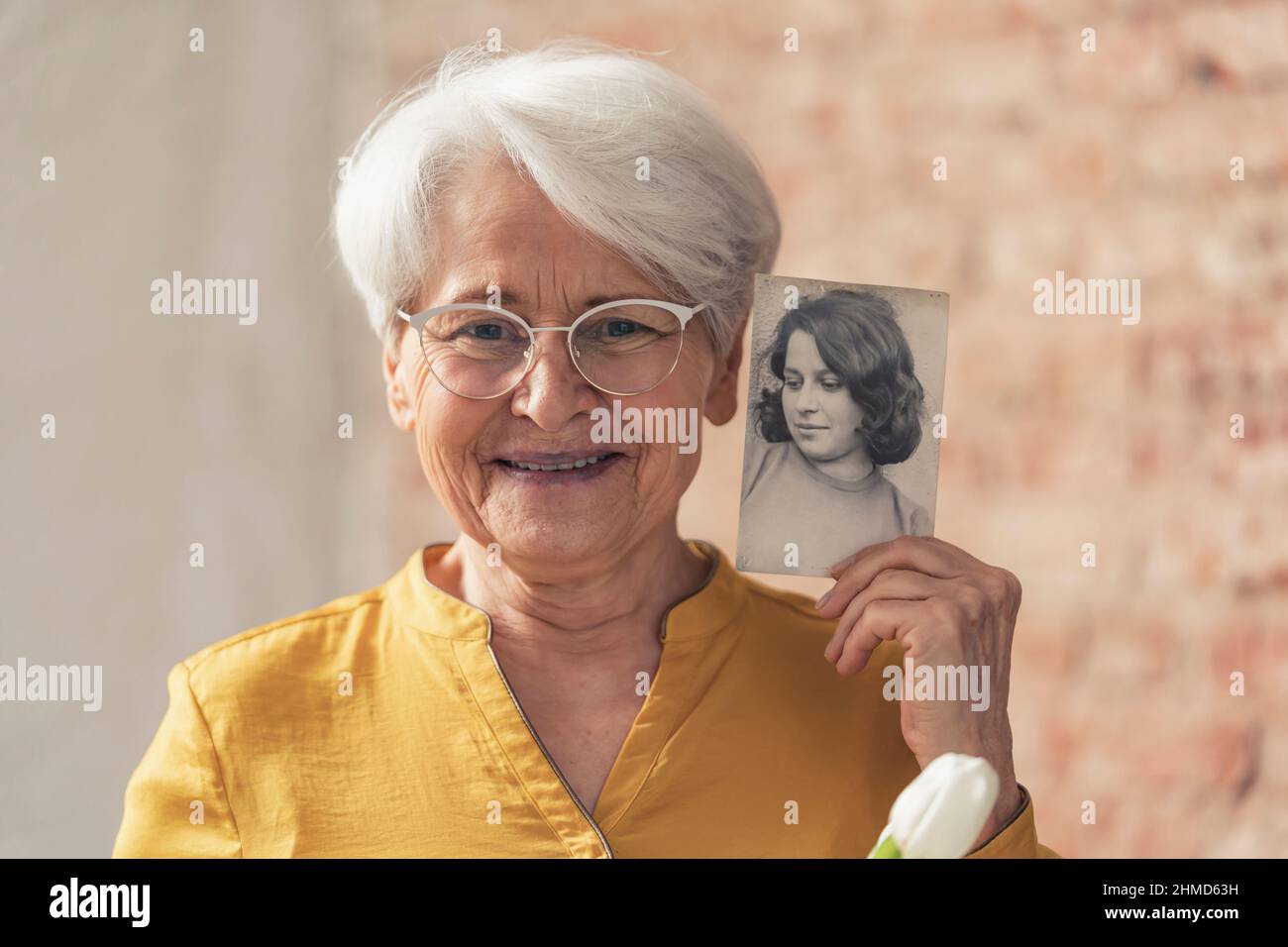 granigliatura e contenuto nonna dai capelli grigi confrontandosi con il suo vecchio ritratto in bianco e nero . Foto di alta qualità Foto Stock