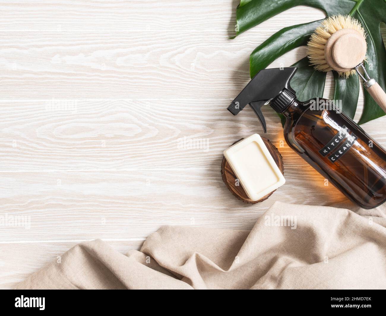 Concetto di pulizia della casa senza rifiuti. Bottiglia ambrata con soluzione di lavaggio, spazzola e sapone su tavola di legno bianco. Vari articoli e ingredienti per eco home c Foto Stock