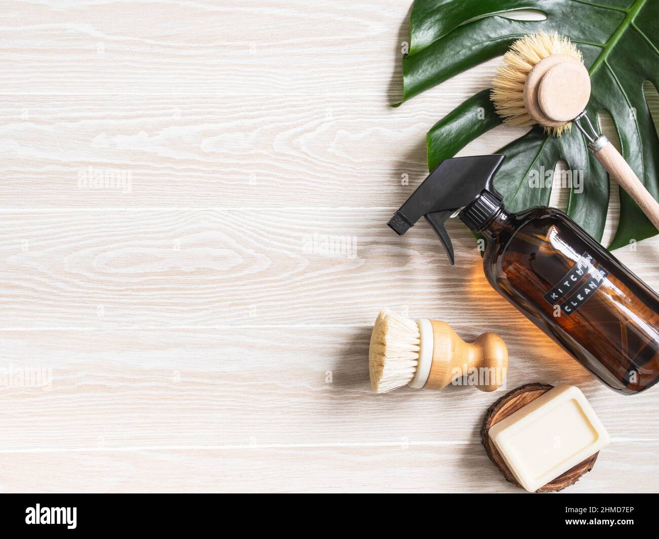 Concetto di pulizia della casa senza rifiuti. Bottiglia ambrata con soluzione di lavaggio, spazzola e sapone su tavola di legno bianco. Vari articoli e ingredienti per eco home c Foto Stock