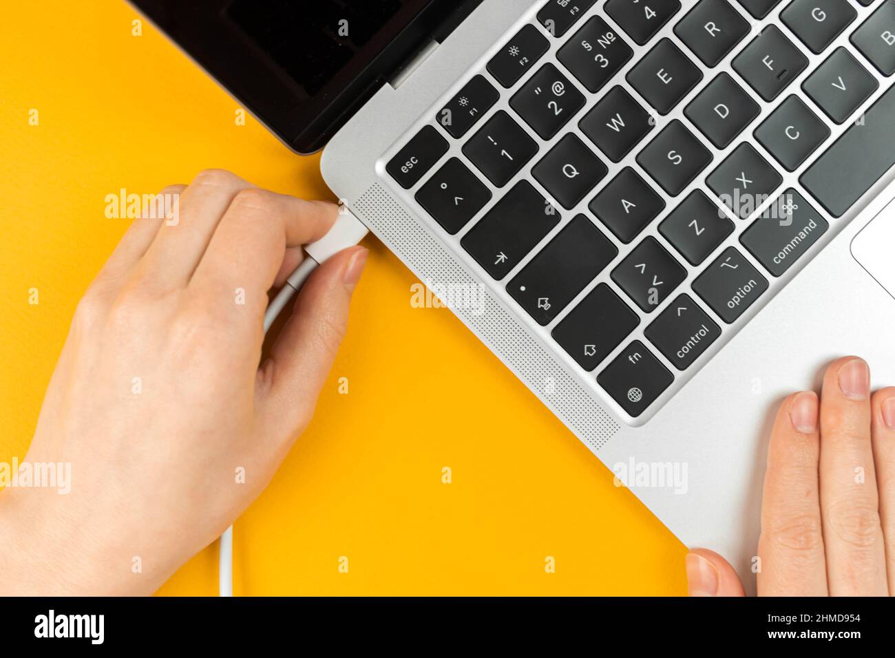 Donna che collega il caricabatterie a un notebook. Porta di ricarica di tipo C. Concetto di batteria scarica Foto Stock