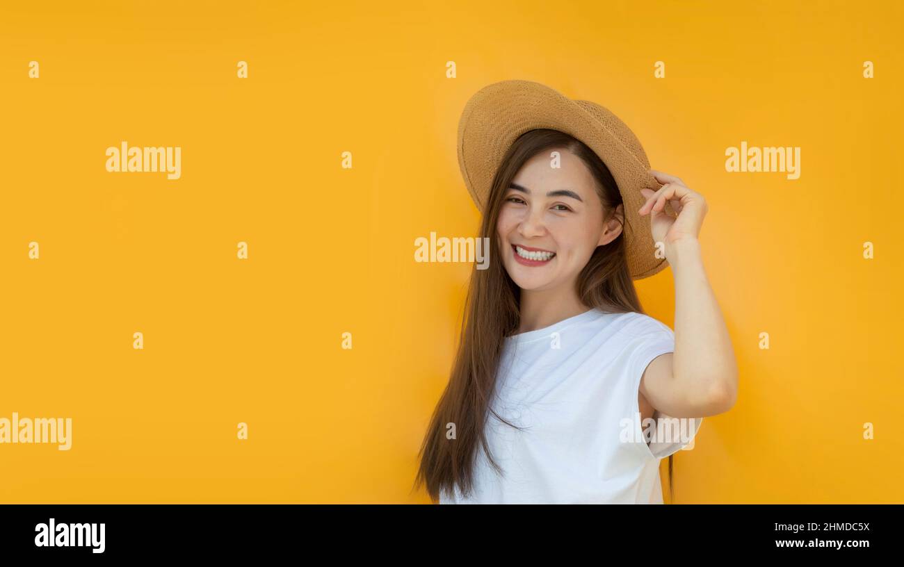 donna asiatica modello sorriso felice con cappello su sfondo giallo isolato su cartellone vuoto mettere testo promozione e prodotto display per l'adveasing Foto Stock