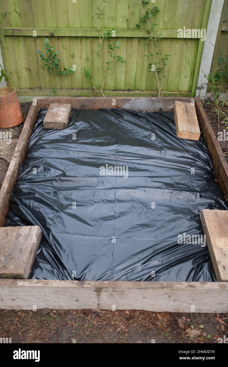 Un letto rialzato in un giardino coperto con lenzuola di plastica Foto Stock