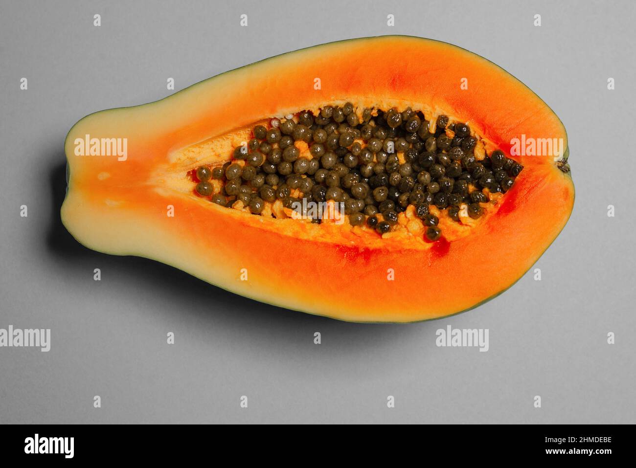 Papaya frutta su sfondo grigio in mani femminili. Frutta tropicale. Metà papaya. Foto Stock