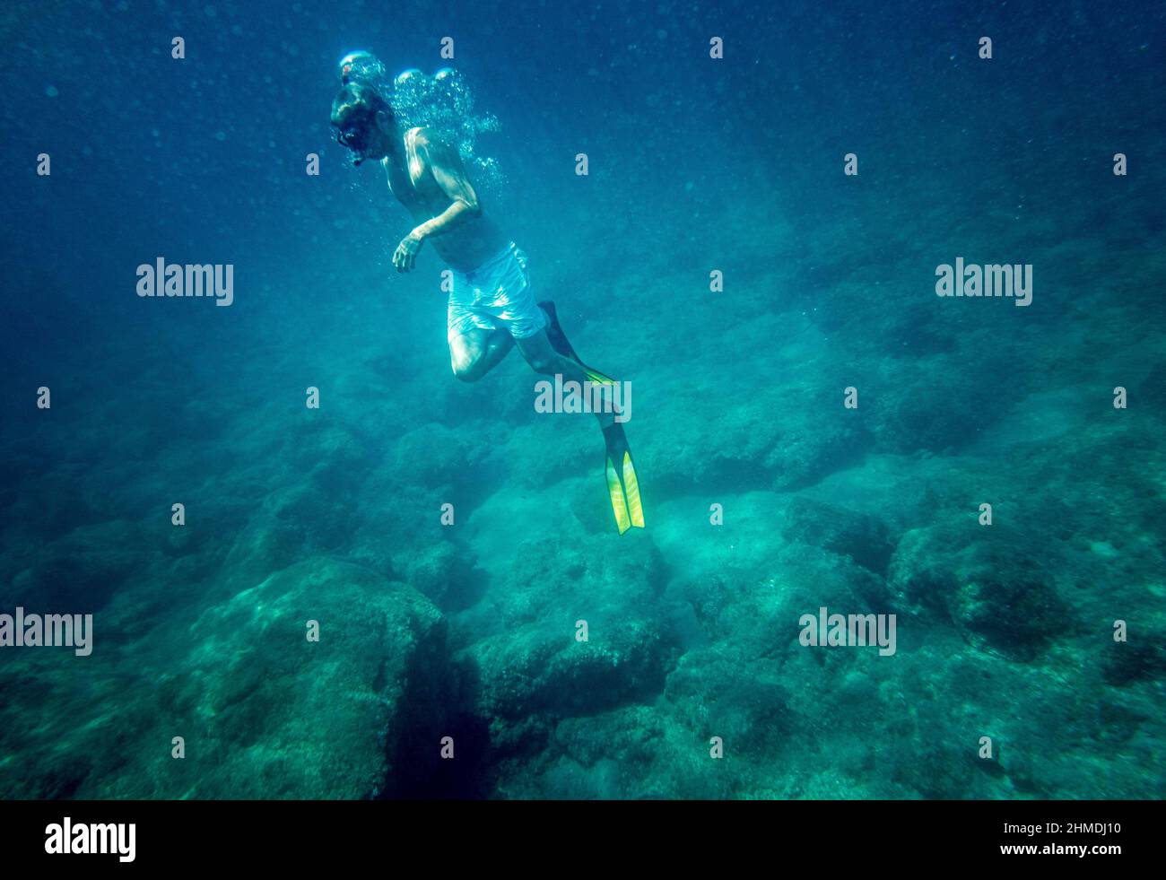 Ragazzo in pantaloncini snorkeling con pinna subacquea Foto Stock