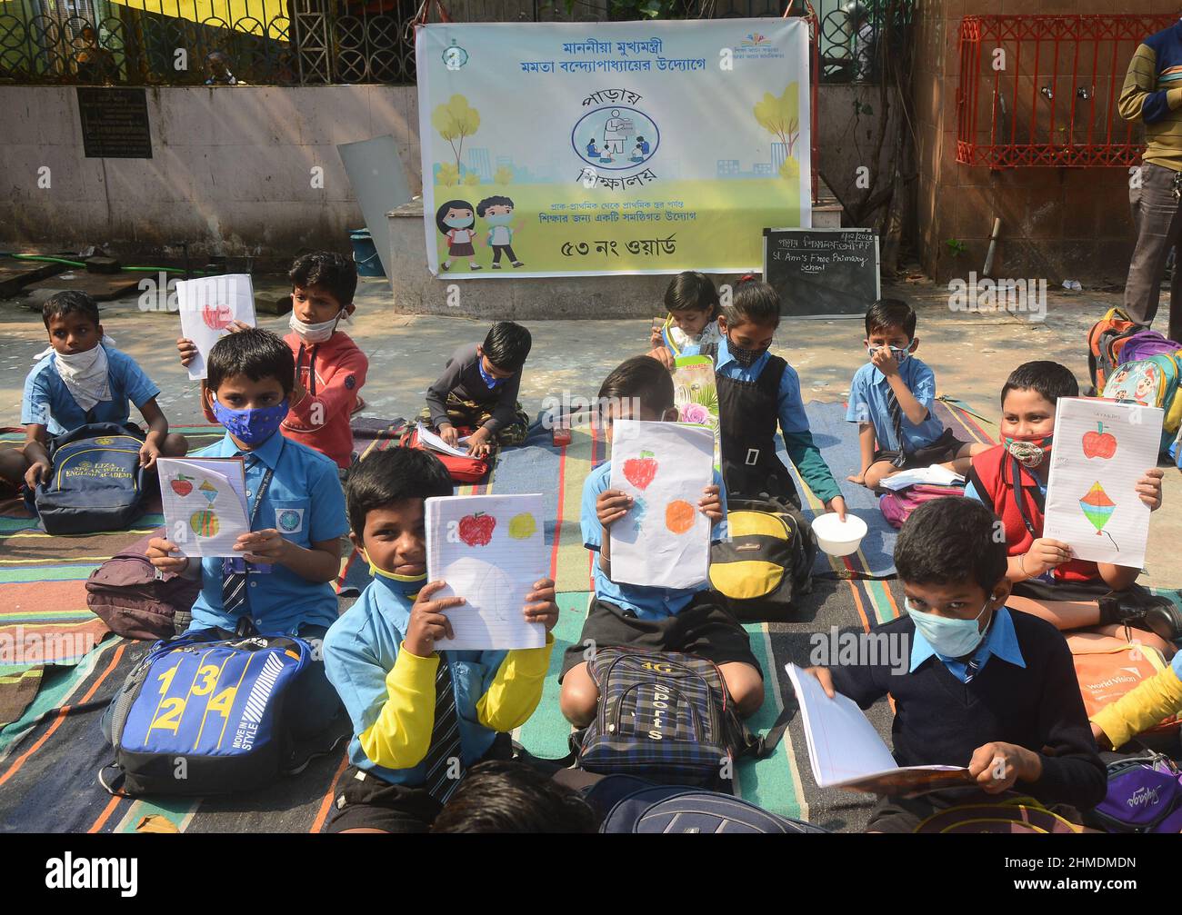 Kolkata, Bengala Occidentale, India. 8th Feb 2022. Le sorelle giocavano con gli studenti in un'aula all'aperto. Gli studenti sono venuti a terra la mattina per lo studio. Si siedono a terra mantenendo protocolli covidi. Indossano maschere. Gli studenti dello stato non sono stati in grado di andare a scuola per molto tempo. Specialmente studenti di classe inferiore. In quest’ottica, il governo statale sta lanciando un progetto per insegnare ai bambini in diverse parti del paese. È stato chiamato ''˜Paraya Shikshalay'. Gli studenti saranno insegnati in uno spazio aperto nel quartiere. L'obiettivo di questo progetto è Th Foto Stock