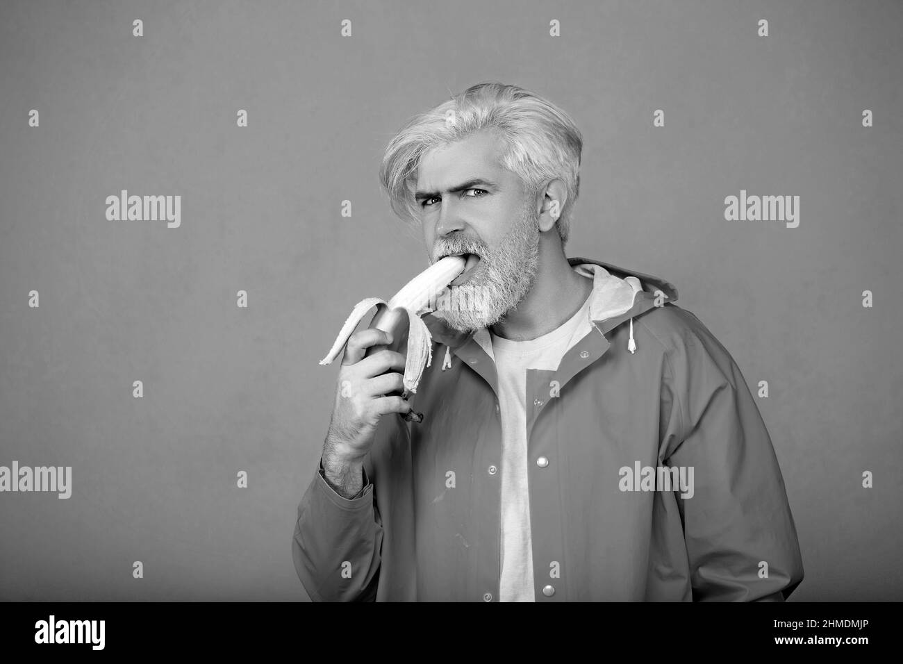 Bel giovane che tiene una banana in mano con la sua bocca aperta Foto Stock
