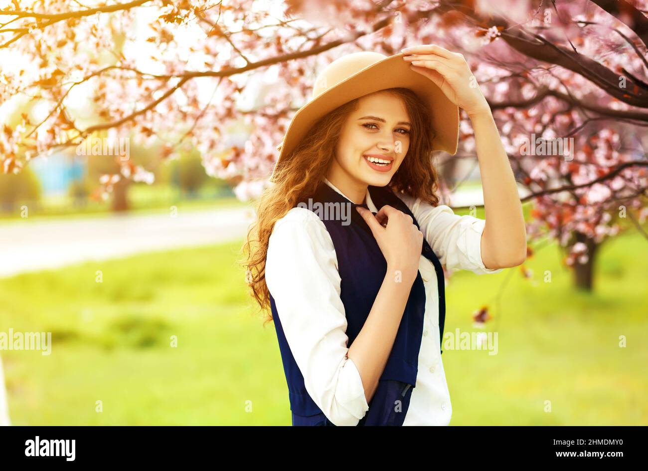 Outdoor Ritratto di giovane bella signora alla moda in posa in prossimità della fioritura tree. Foto Stock