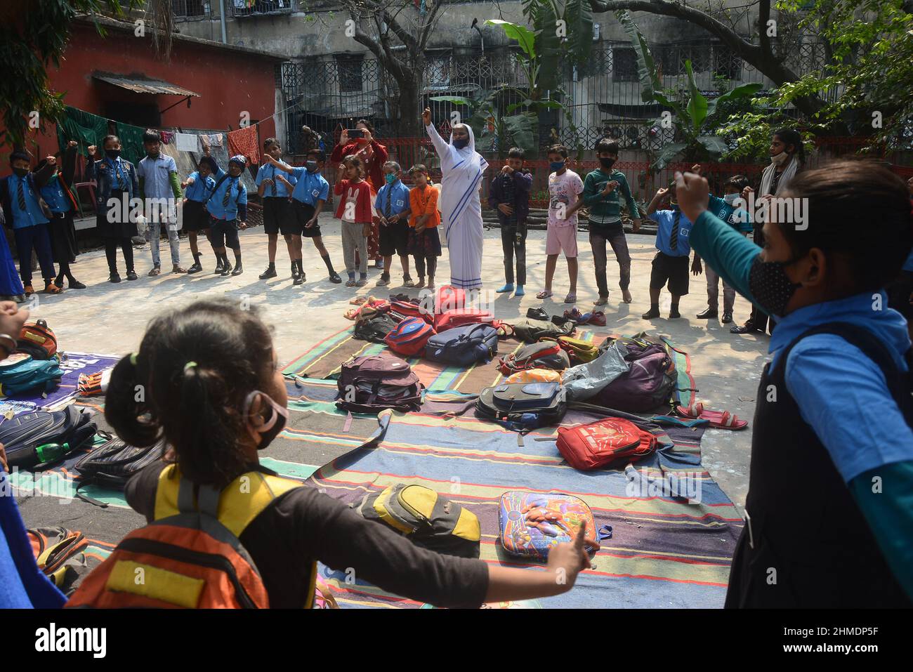 Kolkata, Bengala Occidentale, India. 8th Feb 2022. Le sorelle giocavano con gli studenti in un'aula all'aperto. Gli studenti sono venuti a terra la mattina per lo studio. Si siedono a terra mantenendo protocolli covidi. Indossano maschere. Gli studenti dello stato non sono stati in grado di andare a scuola per molto tempo. Specialmente studenti di classe inferiore. In quest’ottica, il governo statale sta lanciando un progetto per insegnare ai bambini in diverse parti del paese. È stato chiamato ''˜Paraya Shikshalay'. Gli studenti saranno insegnati in uno spazio aperto nel quartiere. L'obiettivo di questo progetto è Th Foto Stock