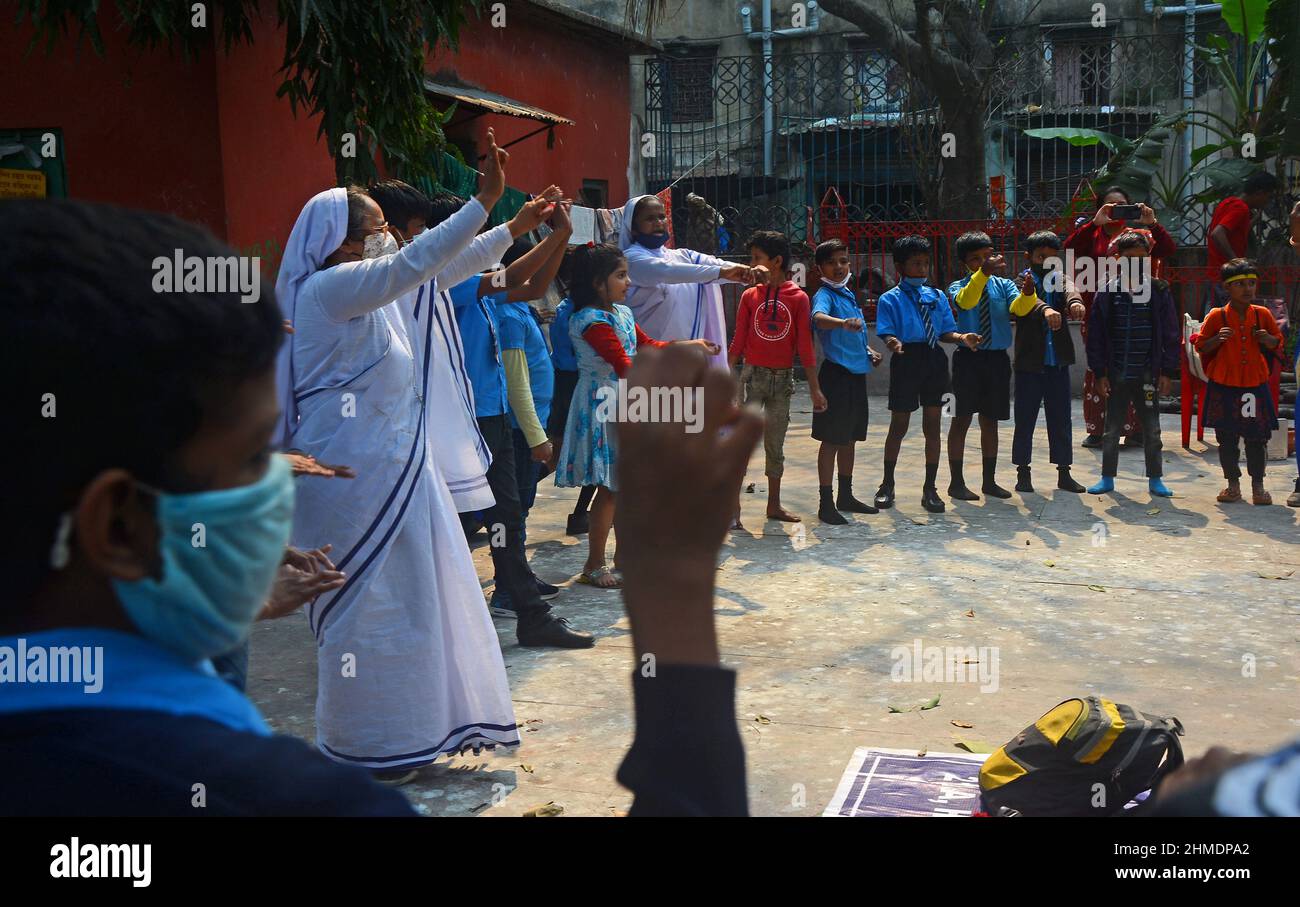 Kolkata, Bengala Occidentale, India. 8th Feb 2022. Le sorelle giocavano con gli studenti in un'aula all'aperto. Gli studenti sono venuti a terra la mattina per lo studio. Si siedono a terra mantenendo protocolli covidi. Indossano maschere. Gli studenti dello stato non sono stati in grado di andare a scuola per molto tempo. Specialmente studenti di classe inferiore. In quest’ottica, il governo statale sta lanciando un progetto per insegnare ai bambini in diverse parti del paese. È stato chiamato ''˜Paraya Shikshalay'. Gli studenti saranno insegnati in uno spazio aperto nel quartiere. L'obiettivo di questo progetto è Th Foto Stock