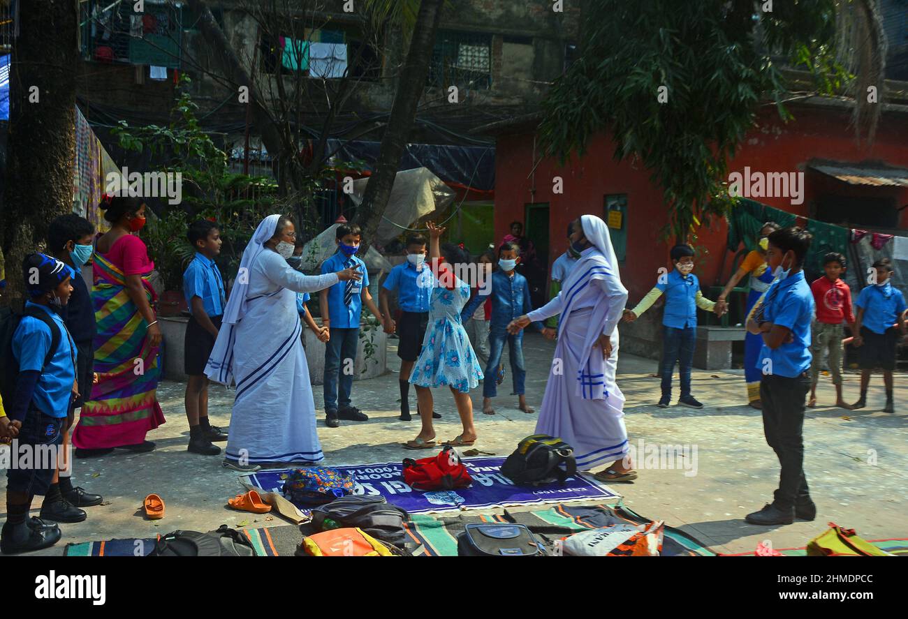 Kolkata, Bengala Occidentale, India. 8th Feb 2022. Le sorelle giocavano con gli studenti in un'aula all'aperto. Gli studenti sono venuti a terra la mattina per lo studio. Si siedono a terra mantenendo protocolli covidi. Indossano maschere. Gli studenti dello stato non sono stati in grado di andare a scuola per molto tempo. Specialmente studenti di classe inferiore. In quest’ottica, il governo statale sta lanciando un progetto per insegnare ai bambini in diverse parti del paese. È stato chiamato ''˜Paraya Shikshalay'. Gli studenti saranno insegnati in uno spazio aperto nel quartiere. L'obiettivo di questo progetto è Th Foto Stock