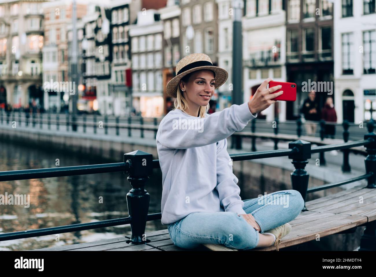 Donna allegra che prende selfie in panchina durante il viaggio Foto Stock