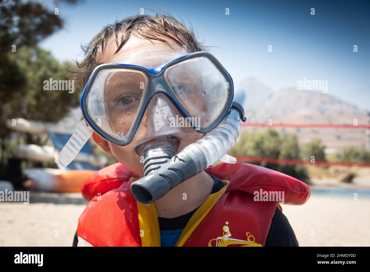 Ragazzo con maschera subacquea e giubbotto salvagente sulla spiaggia Foto Stock