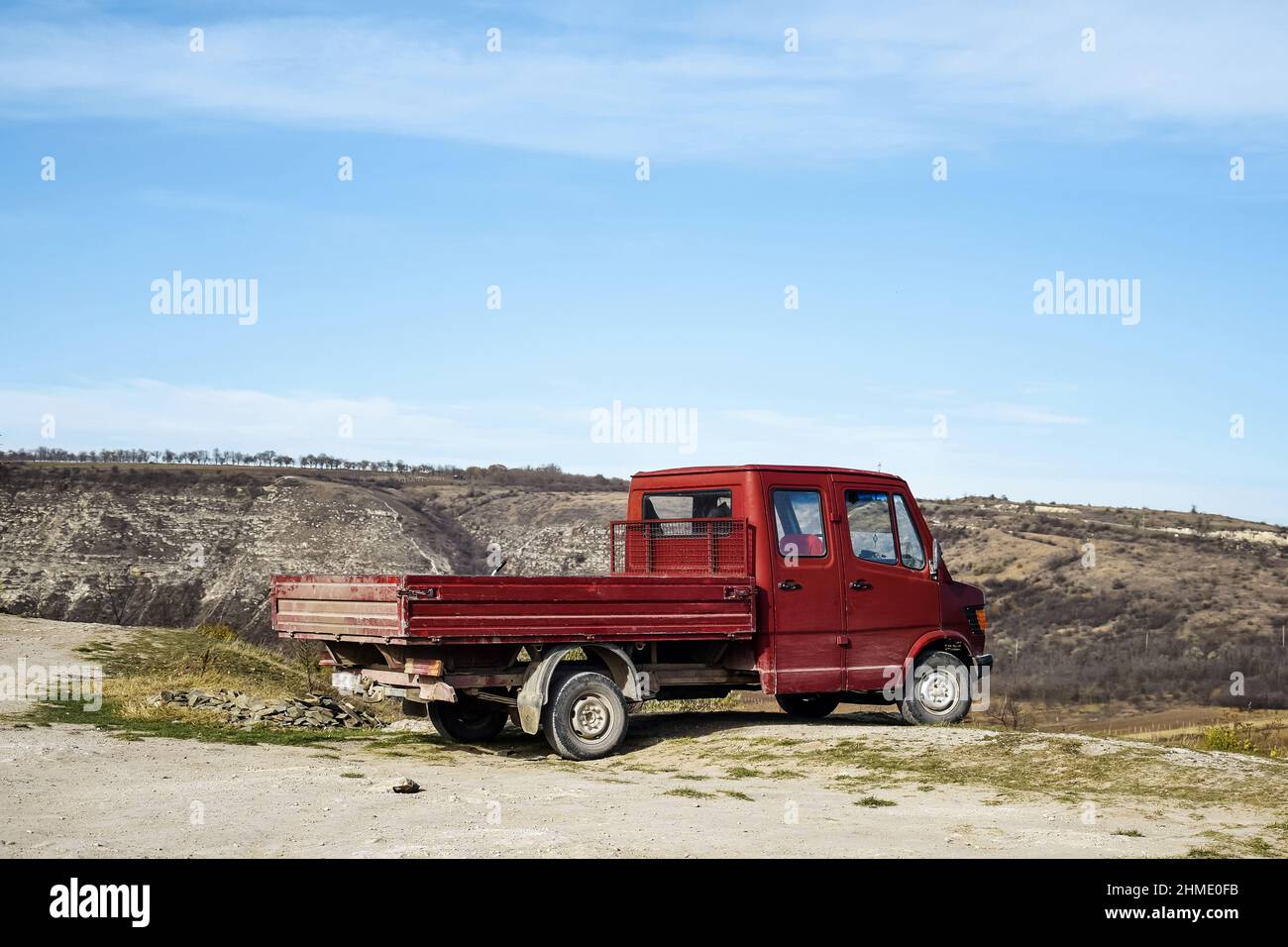 Moldavia, Old Orhei, novembre 2019: Il vecchio camion rosso si ferma al bordo della scogliera. Vista panoramica sulle montagne. Cielo blu. Foto Stock