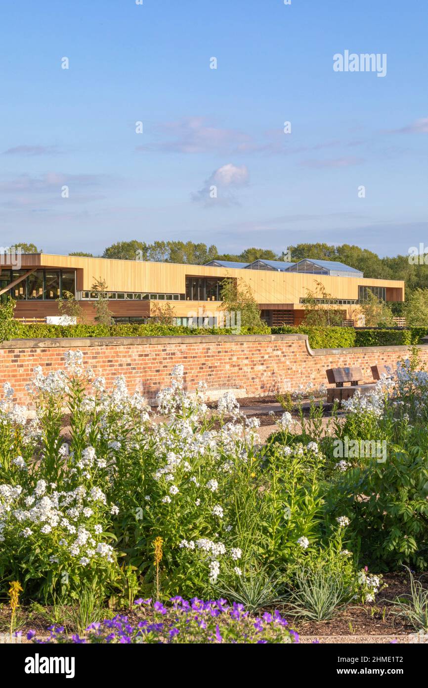 Vista su edificio da giardino murato. Royal Horticultural Society Visitor Center, Worsley, Salford, Regno Unito. Architetto: Hodder & Partners, 2021. Foto Stock
