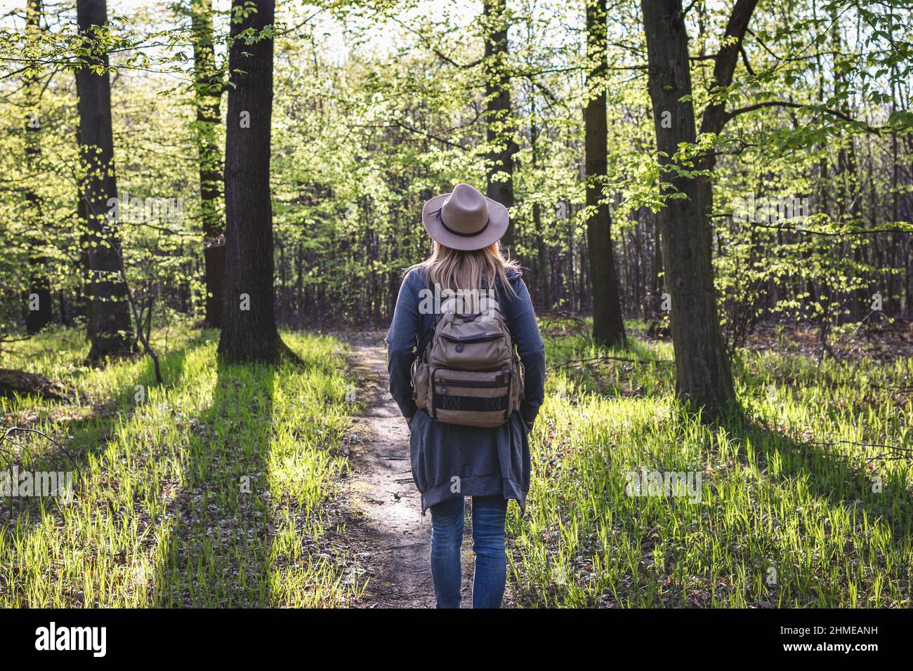 Escursioni nella foresta. Donna con cappello e zaino godendo di escursione all'aperto durante la giornata di sole in primavera Foto Stock
