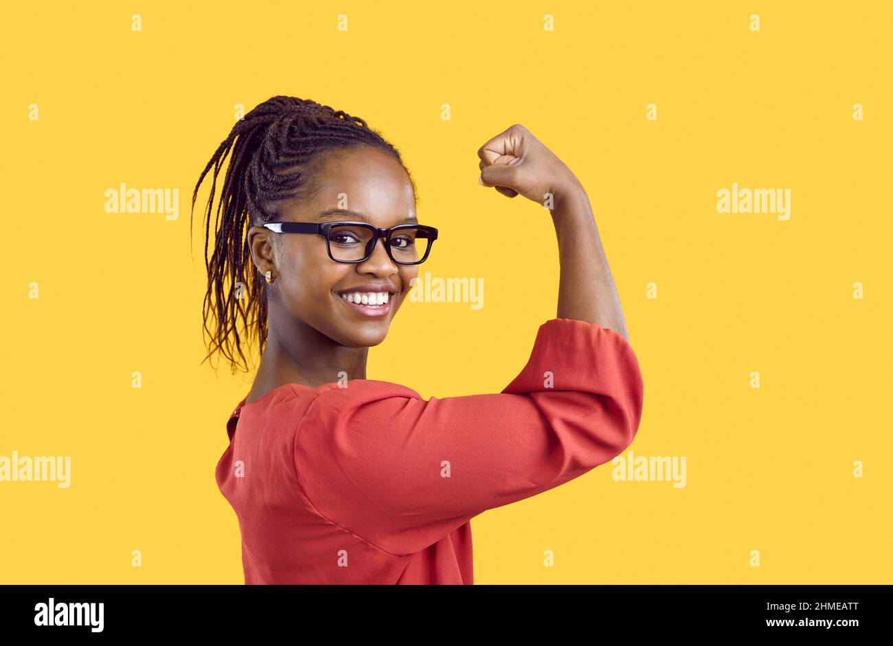 Felice fiducioso forte giovane afroamericana sorride e mostra i suoi muscoli del braccio Foto Stock