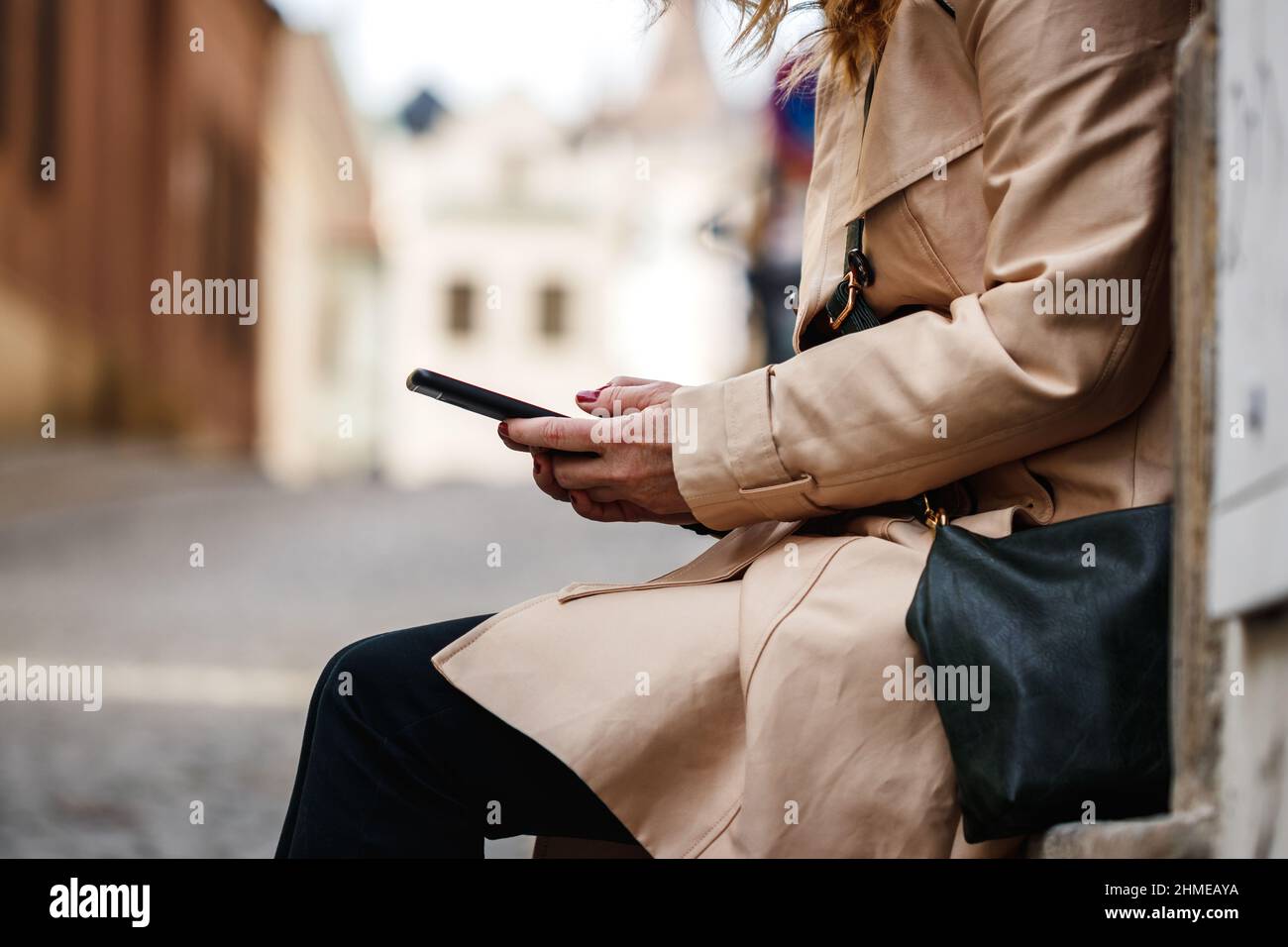 Donna SMS sul suo smartphone in città. Cellulare in mano femminile Foto Stock