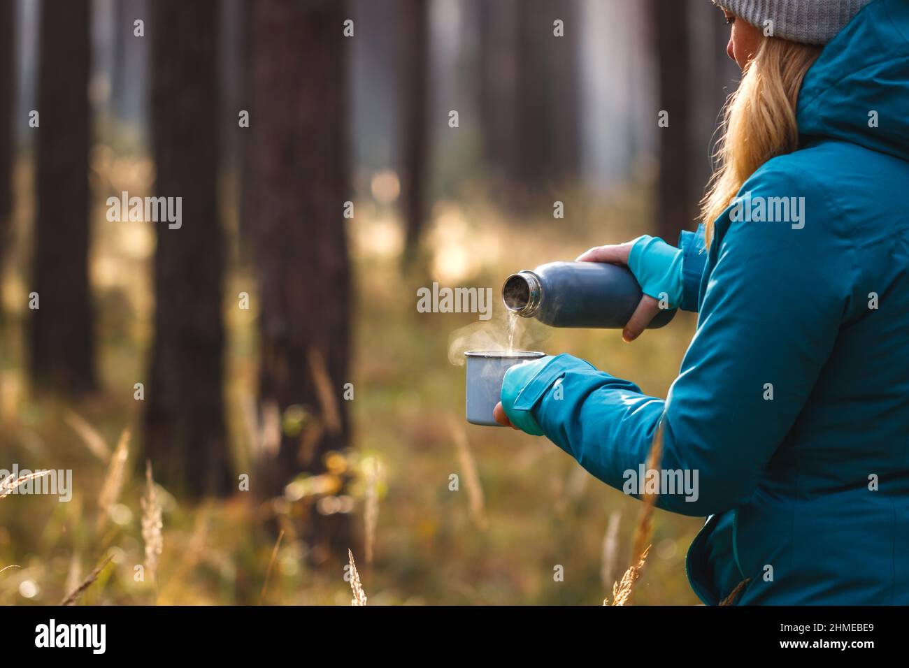 Escursionista versare la bevanda calda da thermos in tazza di viaggio durante il trekking nella foresta. Avventura nella natura Foto Stock